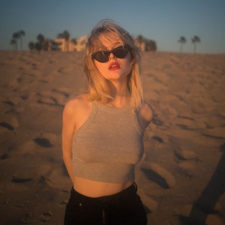 Emily Alyn Lind in a brown top poses for a picture at a beach.